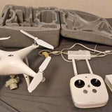 White quadcopter drone with remote controller and batteries in gray case