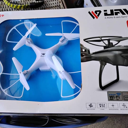 White quadcopter drone with four propellers in retail box