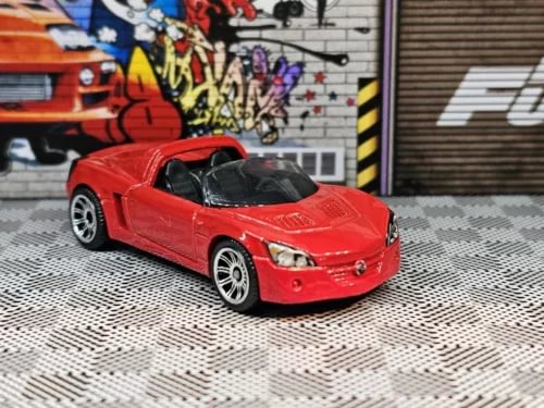 Red diecast sports car, front three-quarter view, detailed grille and headlights.