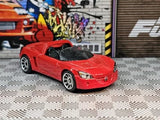 Red diecast sports car, front three-quarter view, detailed grille and headlights.