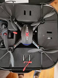 Quadcopter drone with four gray rotors in a hard storage case, top view