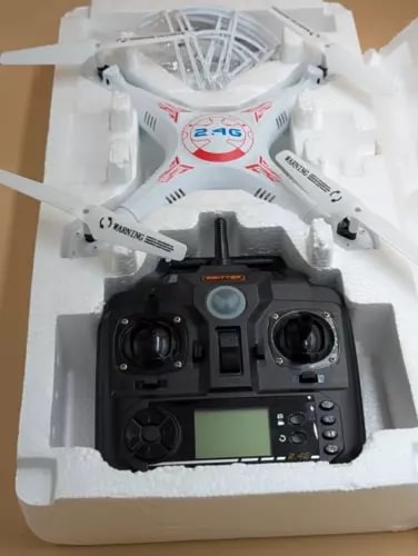 White quadcopter drone with black remote controller, LCD screen and buttons