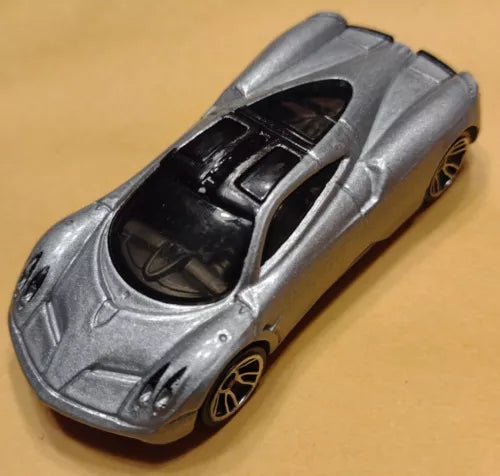 Silver diecast toy supercar with open cockpit and black interior, bronze wheels.