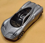 Silver diecast toy supercar with open cockpit and black interior, bronze wheels.