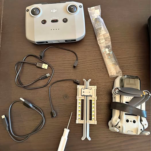 White DJI drone with controller unit and cables, prop tool and protective bag