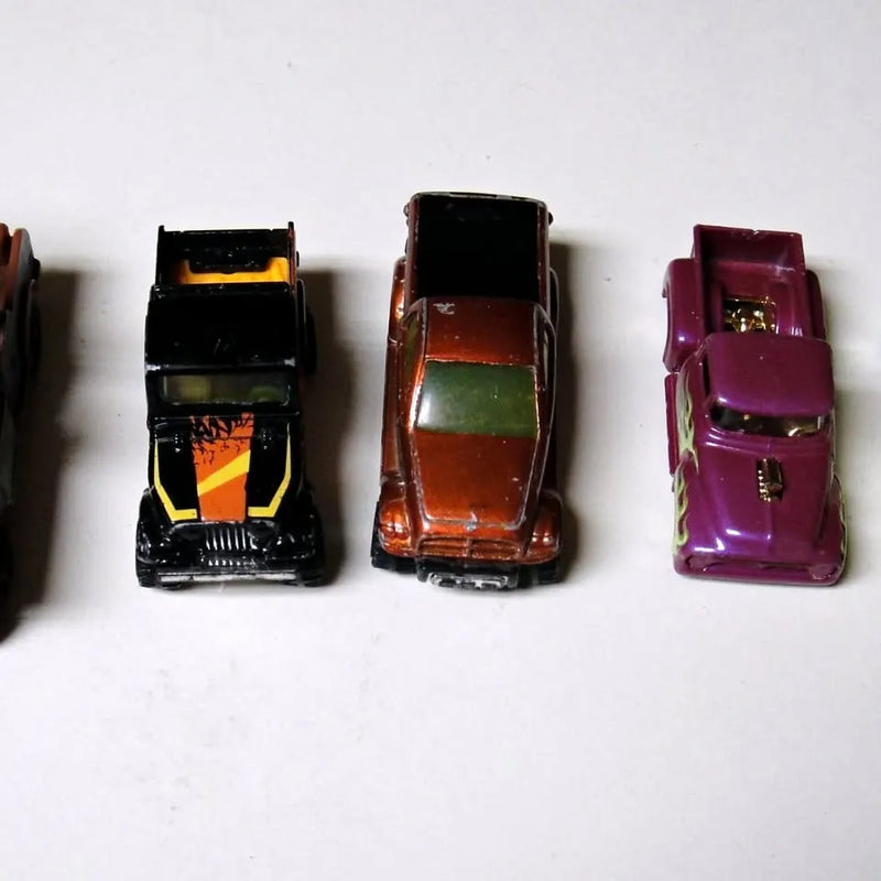 Diecast toy trucks set with three trucks: black/yellow, brown, purple.