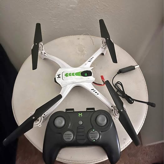 White quadcopter drone with controller radio and green lights