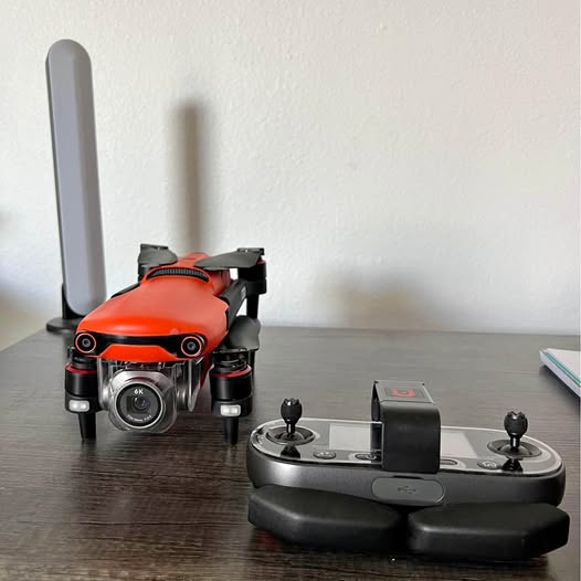 Orange quadcopter drone with camera, controller, and two antennas