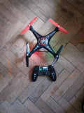 Quadcopter drone with red propellers and black frame, with remote controller