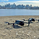 DJI drone with four propellers, black and gray, resting on ground