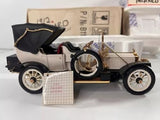 Vintage diecast model car with cream body, dark hood, and gold details