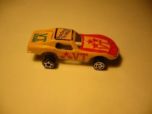 Vintage mini diecast racing car with yellow and orange body, red star graphics.