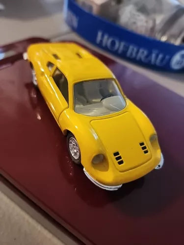 Yellow diecast sports car toy, front three-quarter view, detailed spoke wheels