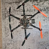 Black hexacopter drone with orange propellers and visible control module on frame