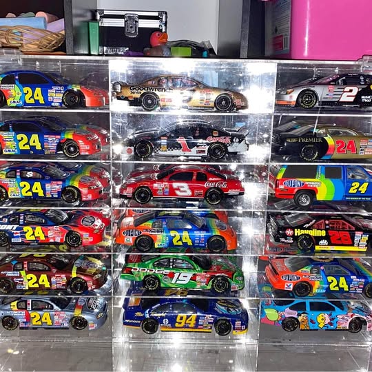 Diecast race car replicas in clear display boxes with team logos and race numbers