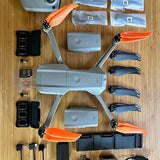 Quadcopter drone with orange propellers, controller, batteries and storage accessories