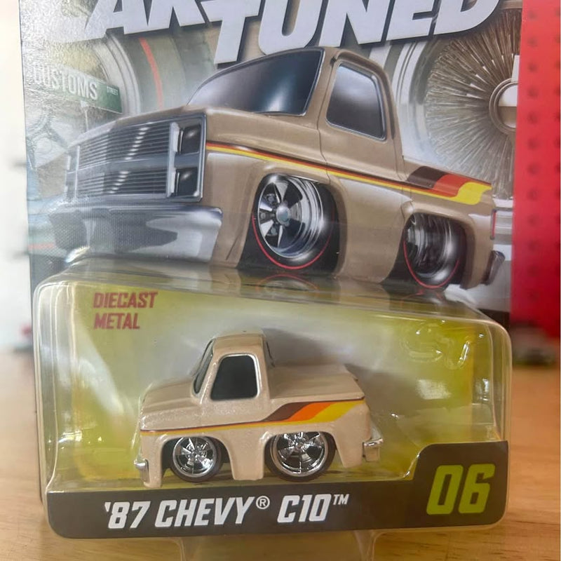Diecast Chevy C10 toy truck with orange stripe, chrome wheels, in clear blister pack