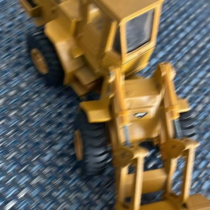 Yellow diecast backhoe loader model with bucket and front loader arms