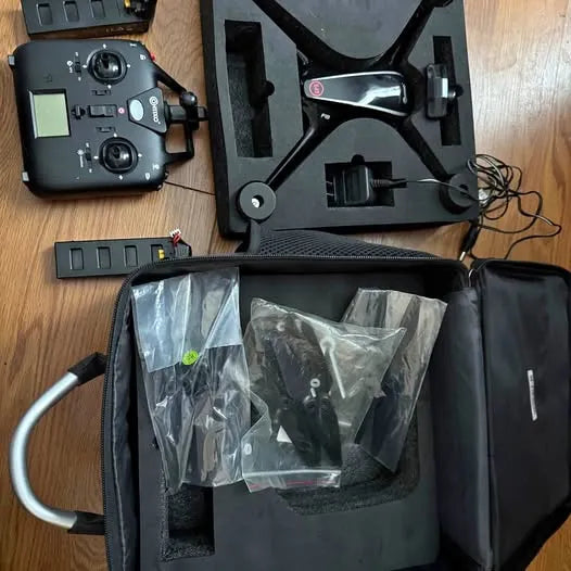 Drone carry case open with foam insert, remote controller, and plastic-wrapped parts