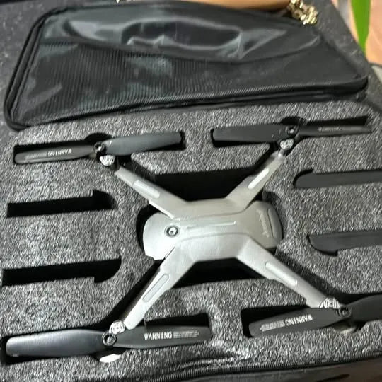 Foldable quadcopter drone with propellers and landing skids in black case
