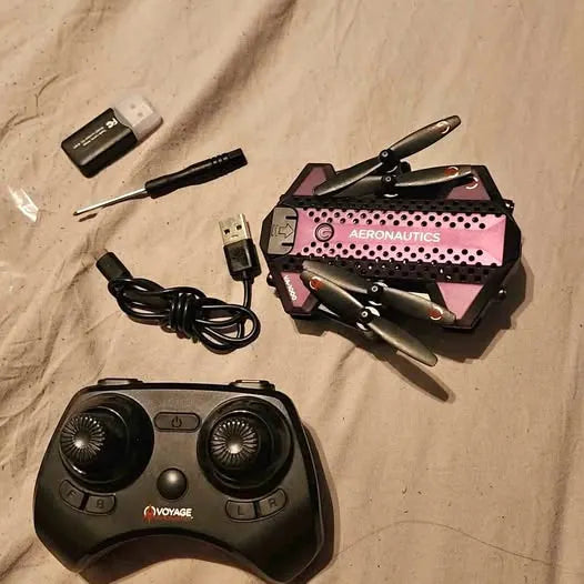 Foldable drone with black remote controller and charging cables