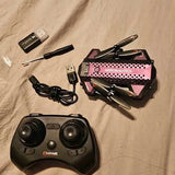 Foldable drone with black remote controller and charging cables