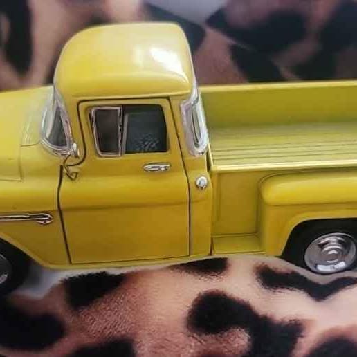 Yellow diecast truck, front and side view with black grille and wheels