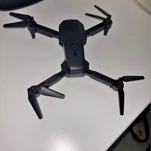 Black quadcopter drone with four propellers and central camera housing