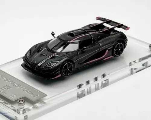 Black diecast sports car model with pink accents, on clear display base, front 3/4 view