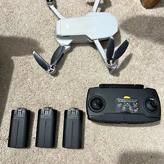 Drone with handheld controller and three spare batteries, front view with propellers