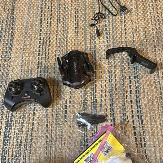 Black drone and handheld controller with charging cable and storage bag