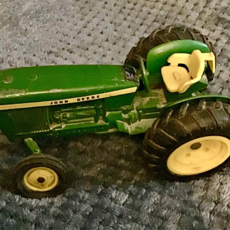 Green die-cast John Deere tractor toy with front wheel and steering details