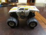 Gray and black diecast monster truck with oversized wheels and yellow graphics