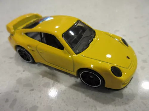 Yellow diecast toy race car with black wheels and windows, front three-quarter view