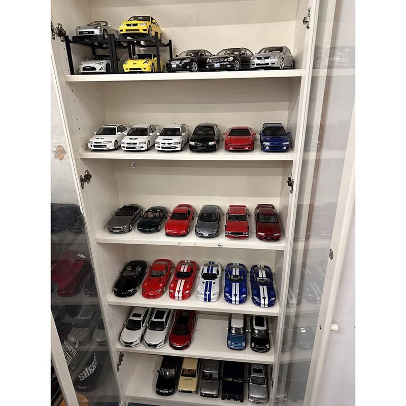 Diecast model car collection in a white display cabinet, assorted colors and styles