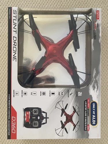 Red quadcopter stunt drone in retail box with controller and app icons