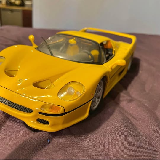 Yellow Ferrari diecast sports car with open wheels, front three-quarter view