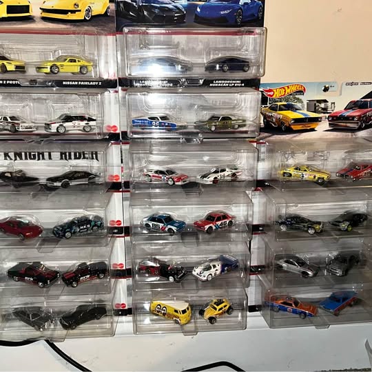 Assorted diecast toy cars in clear plastic display cases, multiple rows