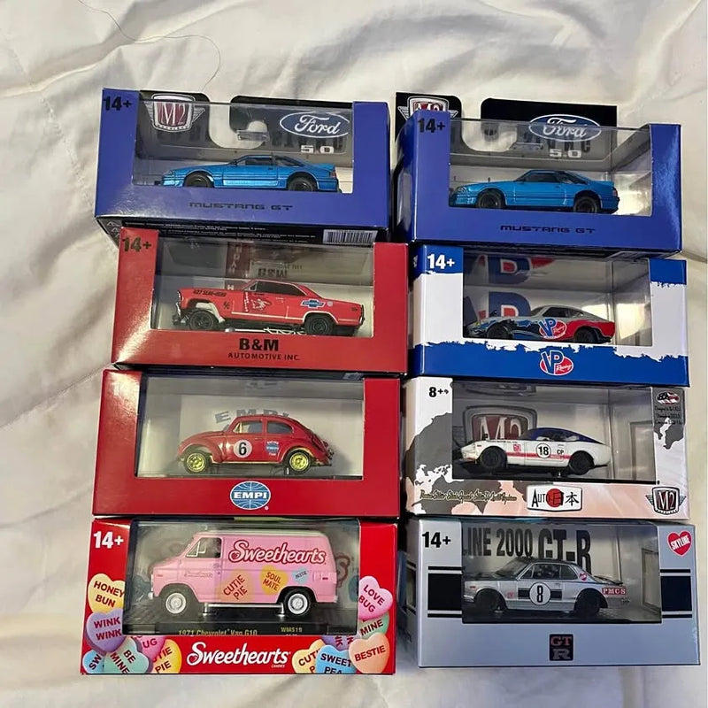 M2 diecast car models in retail boxes, assorted designs, 14+ age labels visible