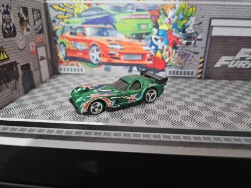 Green race car diecast model with orange graphics, hood stripe, black wheels