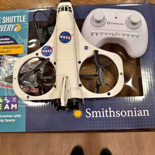 White quadcopter drone with four propellers, NASA and Smithsonian decals, front view
