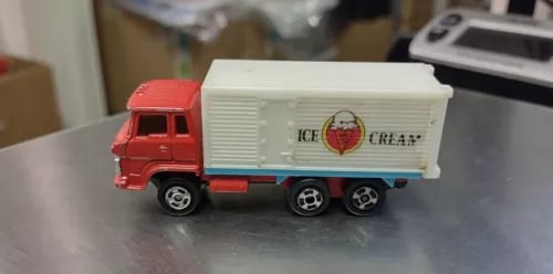 Diecast toy delivery truck with red cab and white ice cream box trailer