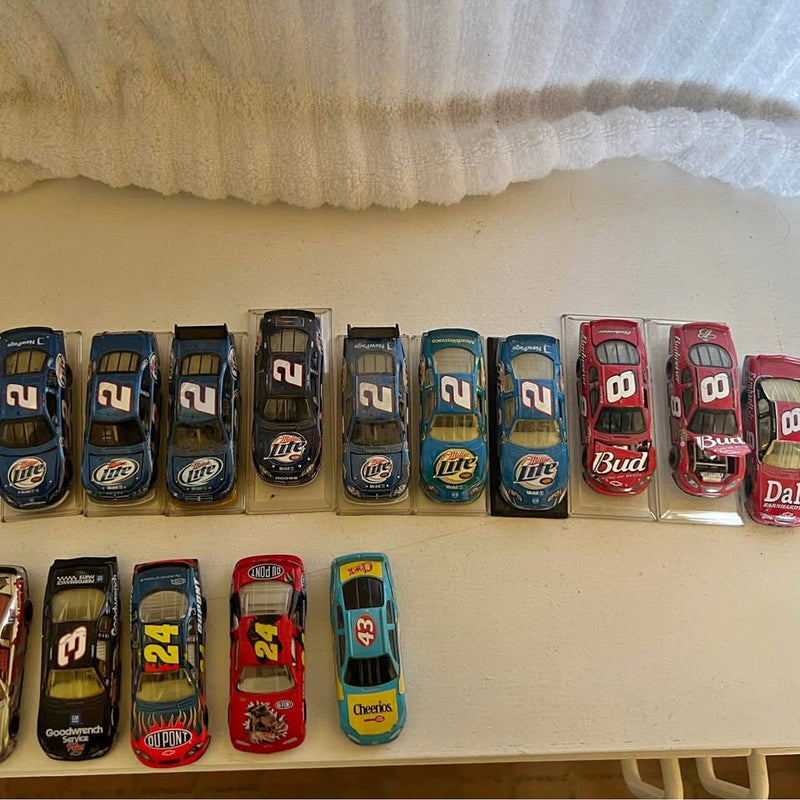 1:64 NASCAR diecast race car assortment in clear display boxes, row on shelf