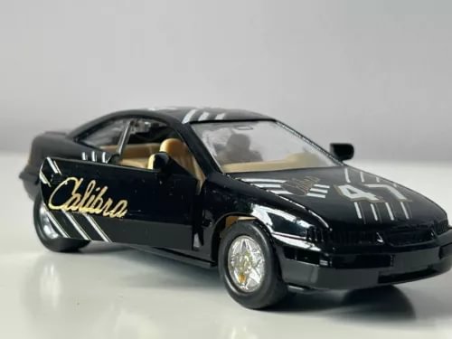 Black diecast race car model with hood graphics and open driver door