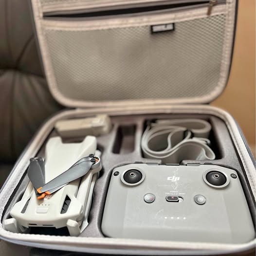 Foldable drone in hard-shell carrying case with controller, cables, and prop guards
