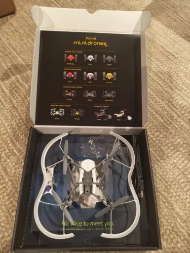 White mini quadcopter drone in open box, with four arms and landing gear visible