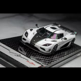 White and black carbon diecast sports car model with visible cockpit interior, front 3/4