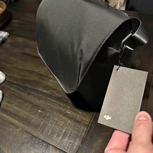 Dark gray textured drone bag with side handle and hanging DJI tag