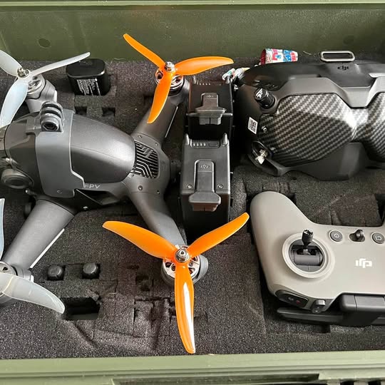 DJI FPV drone with orange propellers and matching controller, gray and black