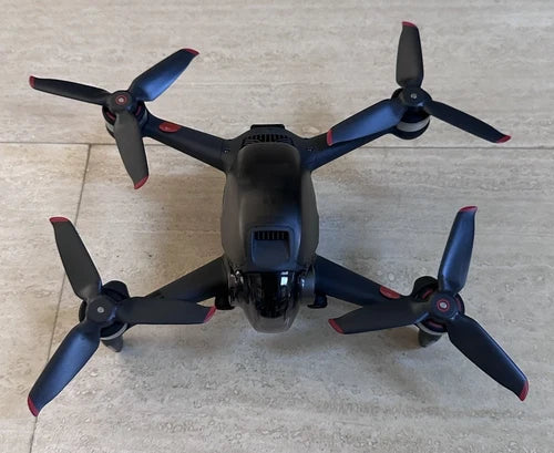 FPV drone aircraft with four blue-tipped propellers and black body